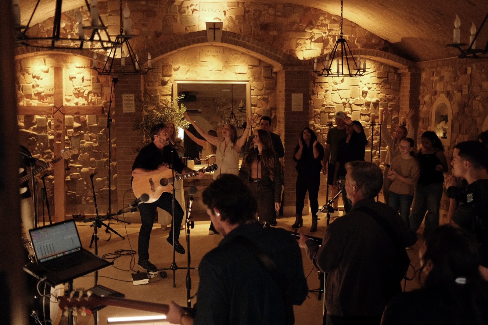 Evening worship in the candlelit Wine Cave at The Hidden Encounter, hands raised
