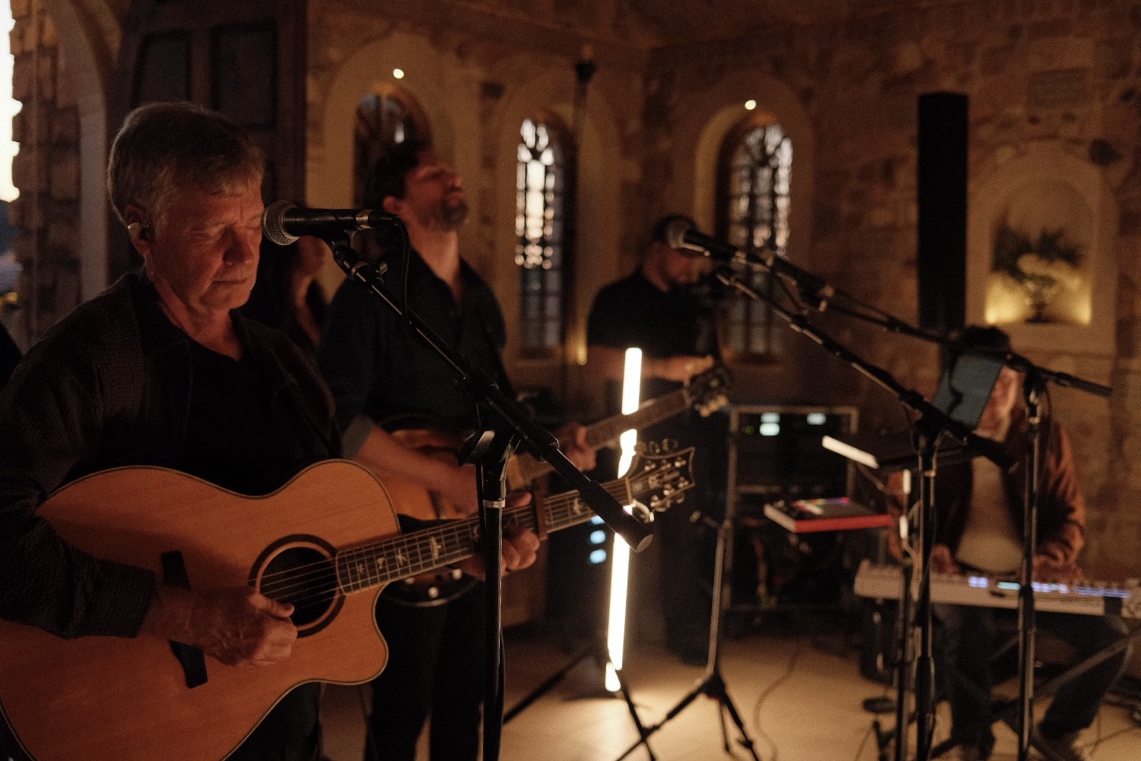 Acoustic worship musicians playing in the chapel by warm light during an evening session