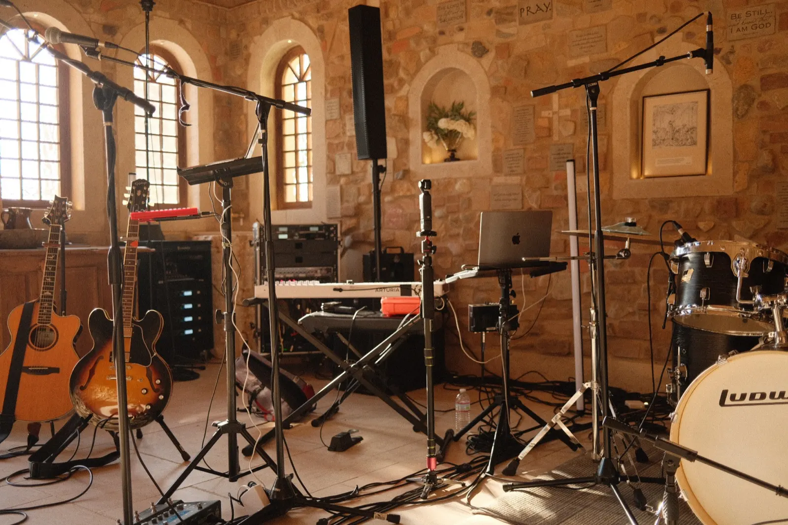 Instruments and microphones arranged in the chapel, the words Be Still I Am God inscribed on the stone wall