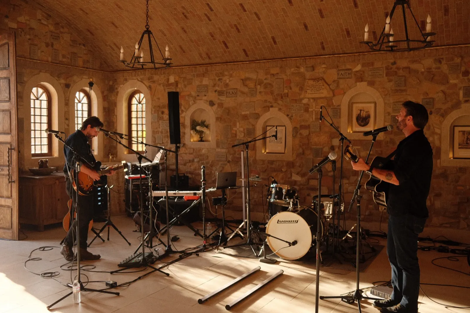 Musicians rehearsing inside the Zion Chapel, Scripture set into the stone walls and arched windows behind