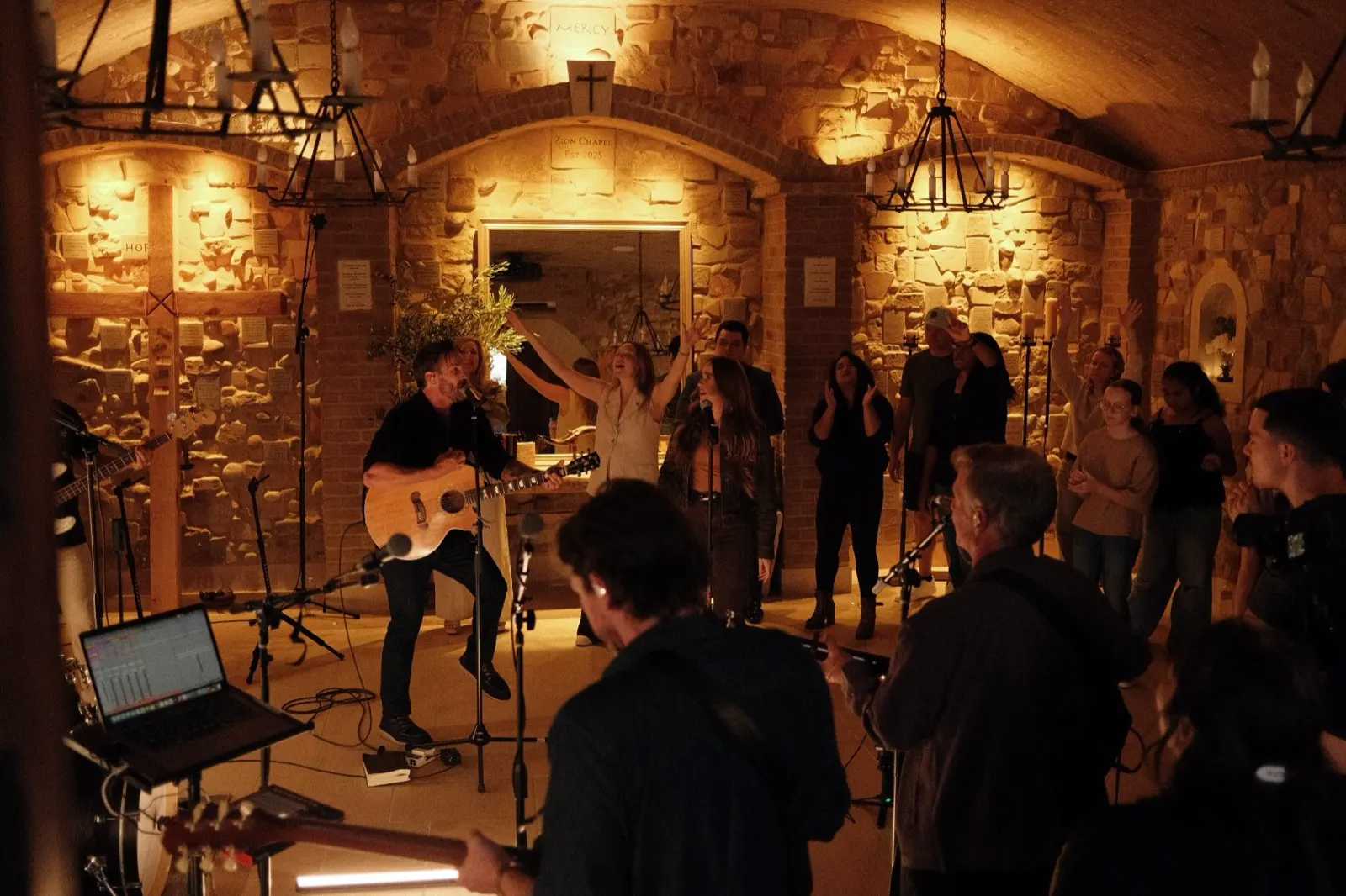 Evening worship in the candlelit Wine Cave at The Hidden Encounter, hands raised