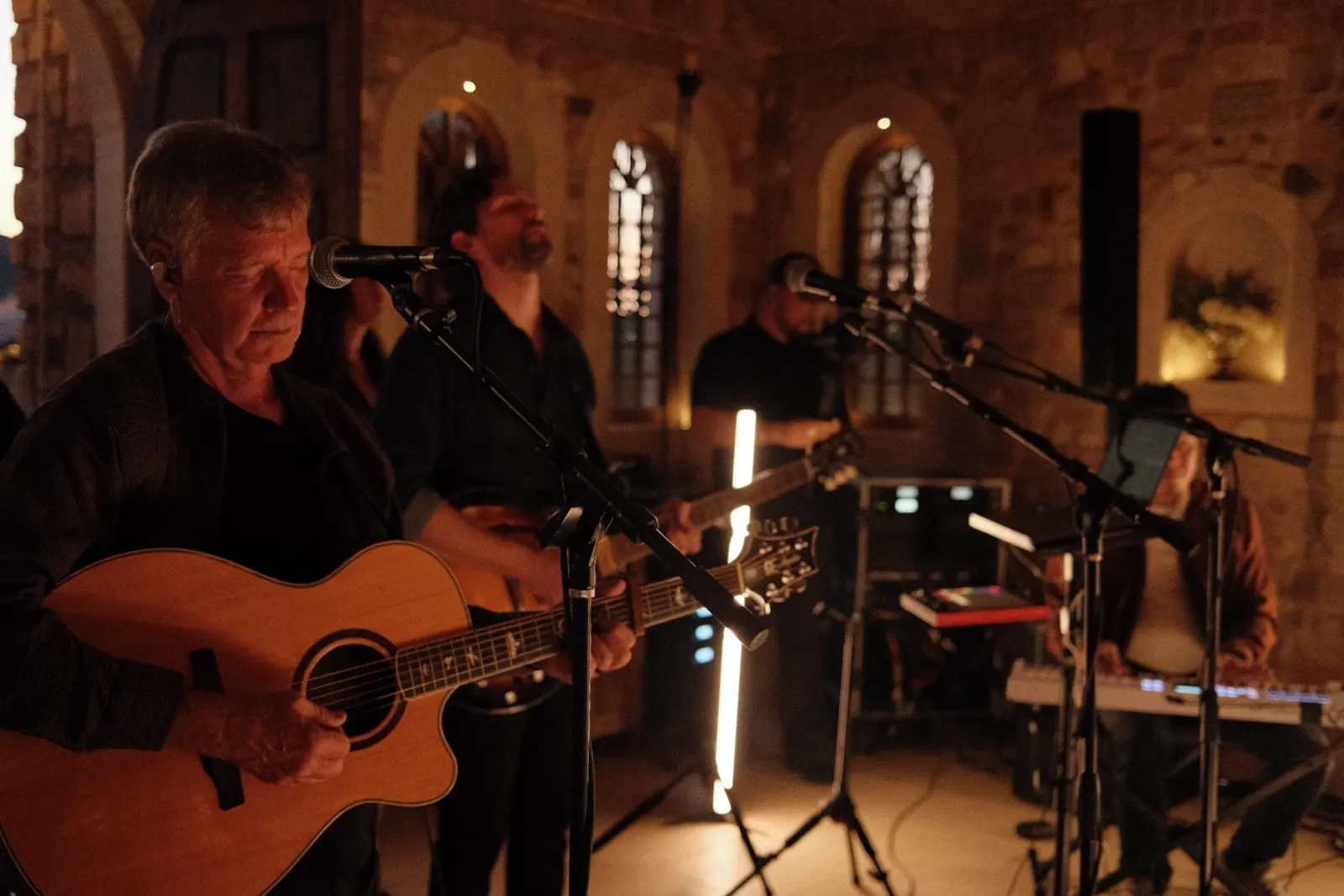 Acoustic worship musicians playing in the chapel by warm light during an evening session
