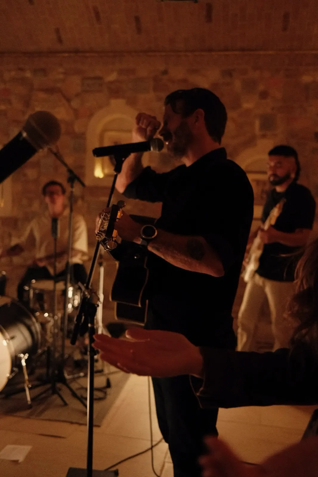 A vocalist singing with a raised microphone during candlelit evening worship at The Hidden Encounter
