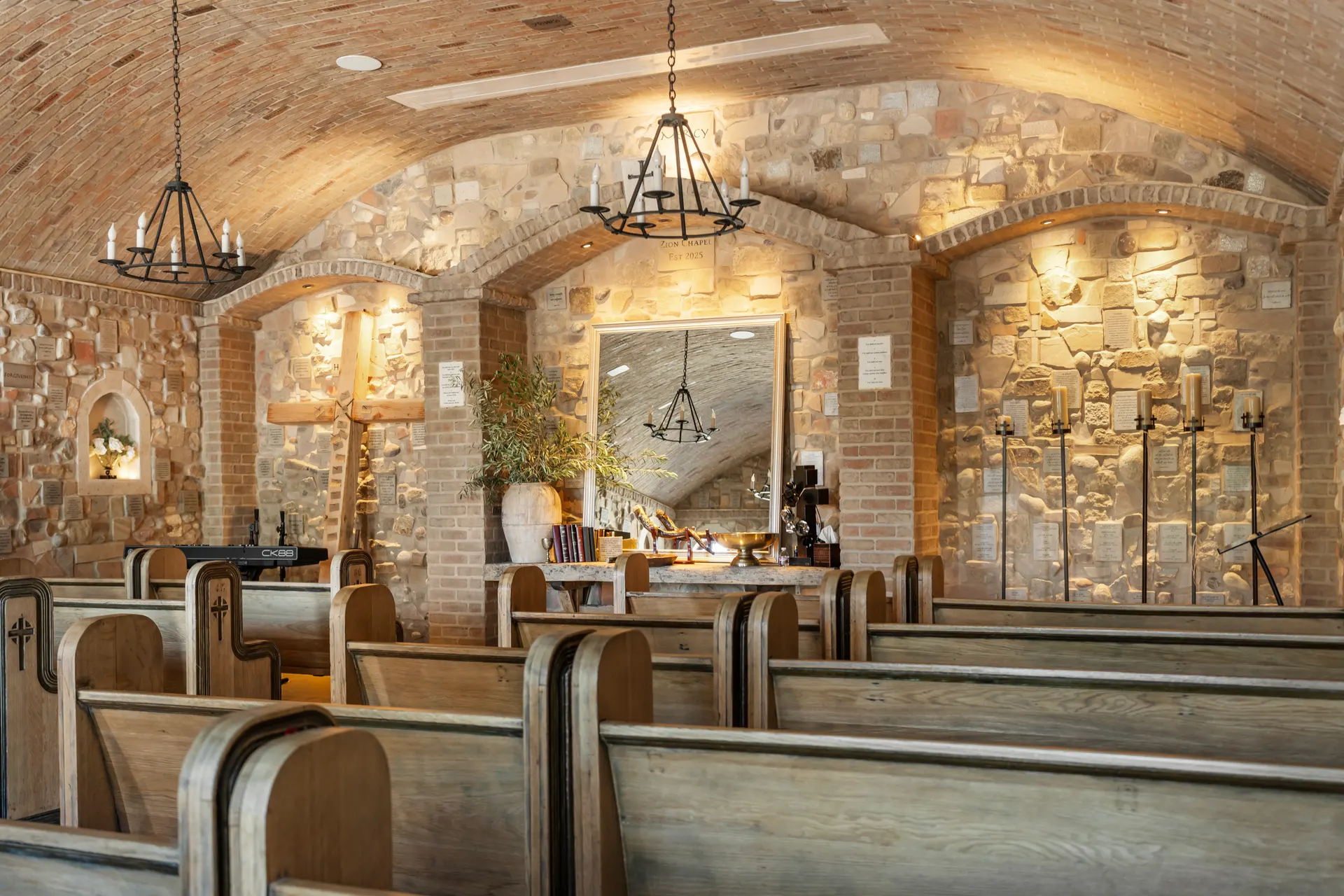 Chapel interior from the side aisle, arched alcoves and candle sconces along the stone wall