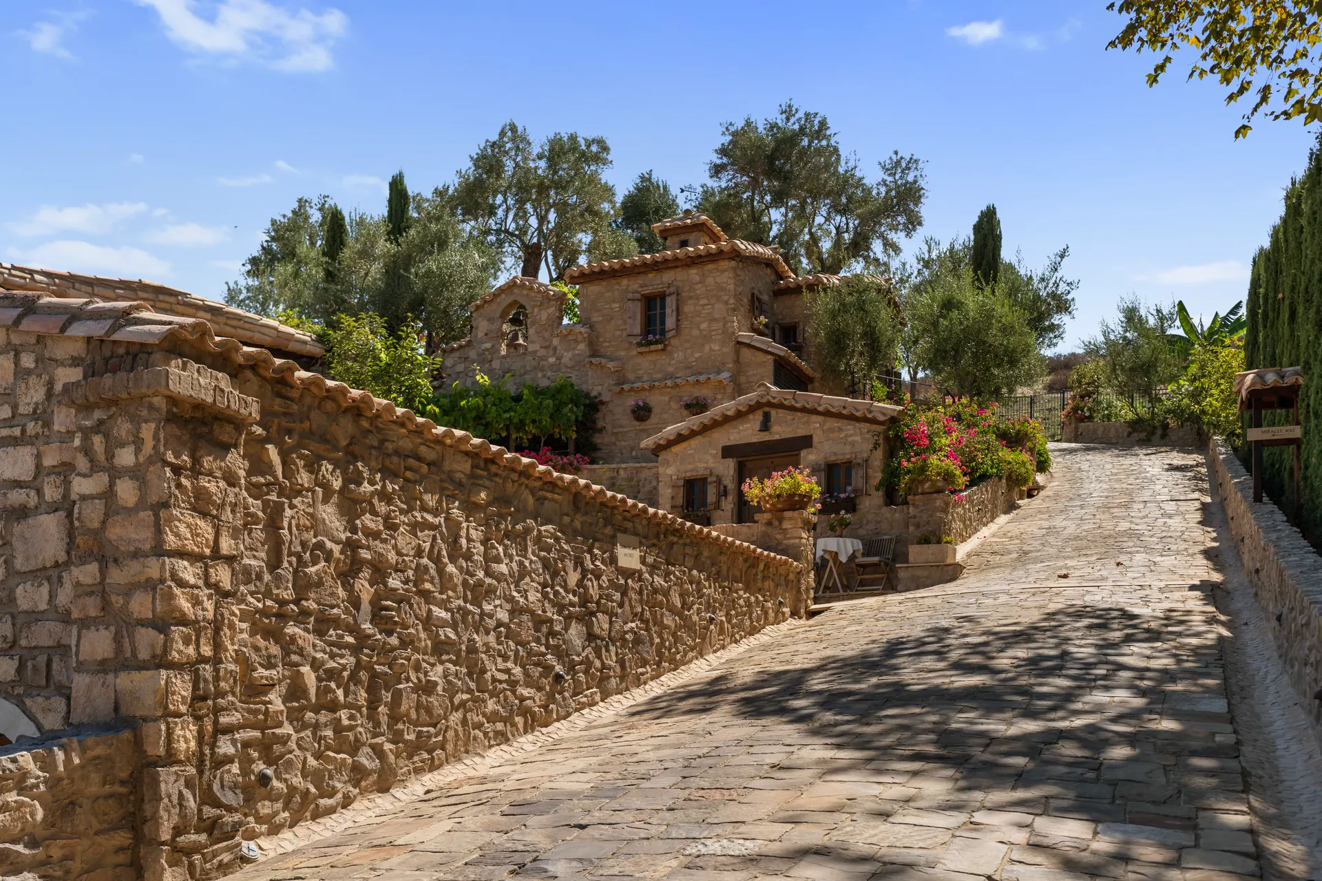 Cobbled drive climbing between stone walls toward the tiled roofs above