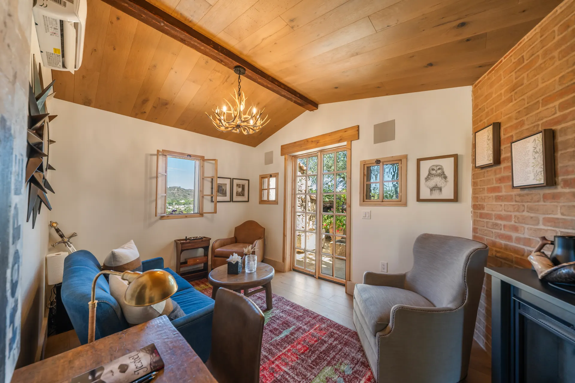 Sitting room from the hearth, antler chandelier above, glazed doors opening to the terrace