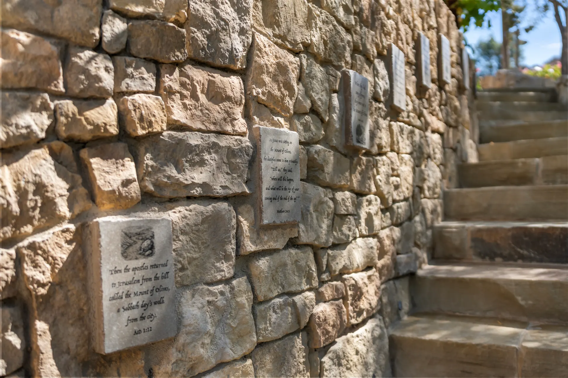 Scripture plaques set into the stone wall of a stair, steps climbing past them