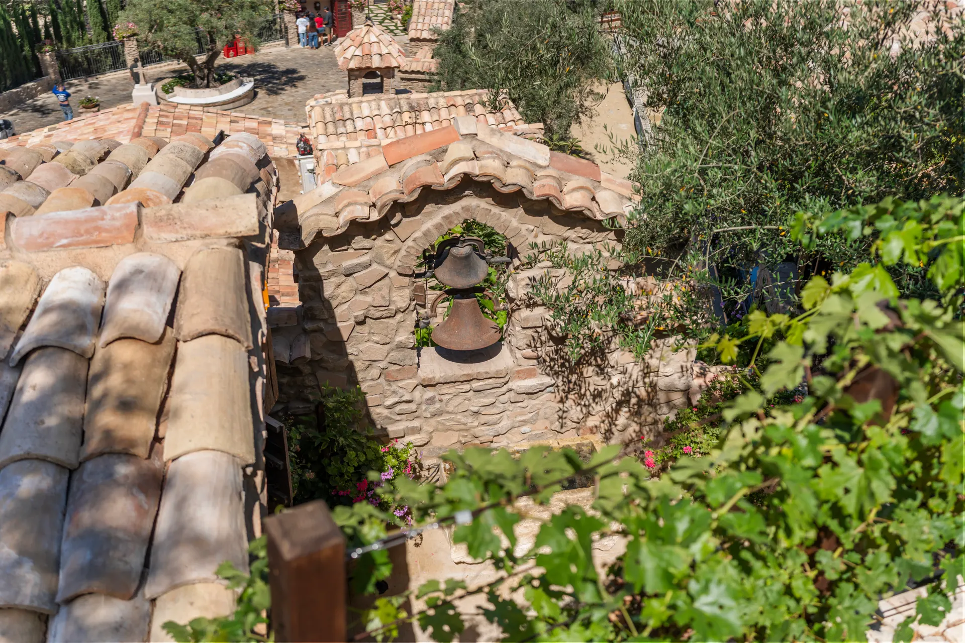 Clay tile roofs stepping down the hillside, vines growing across the ridge
