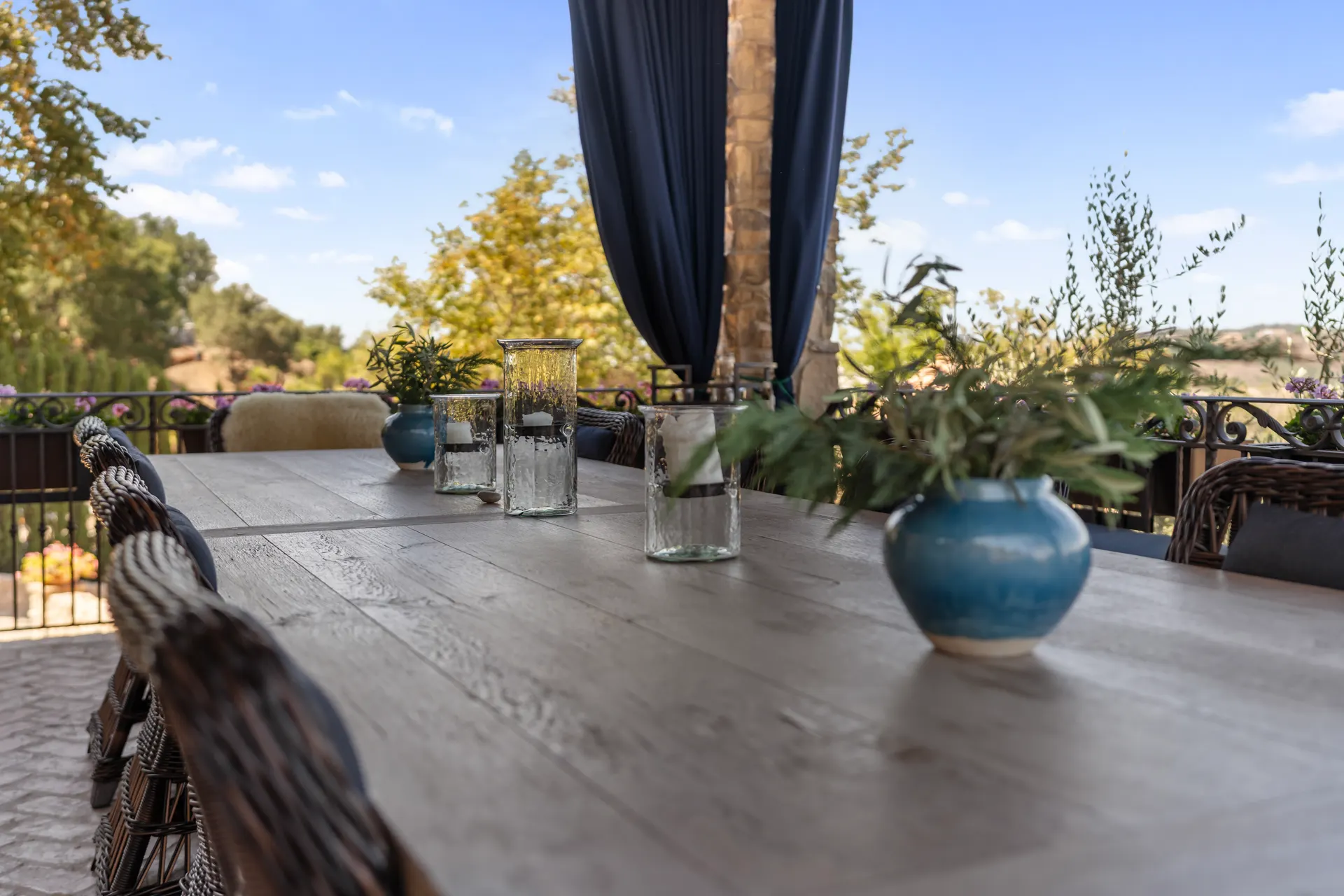 Table detail with a blue glazed vessel and glassware on weathered timber