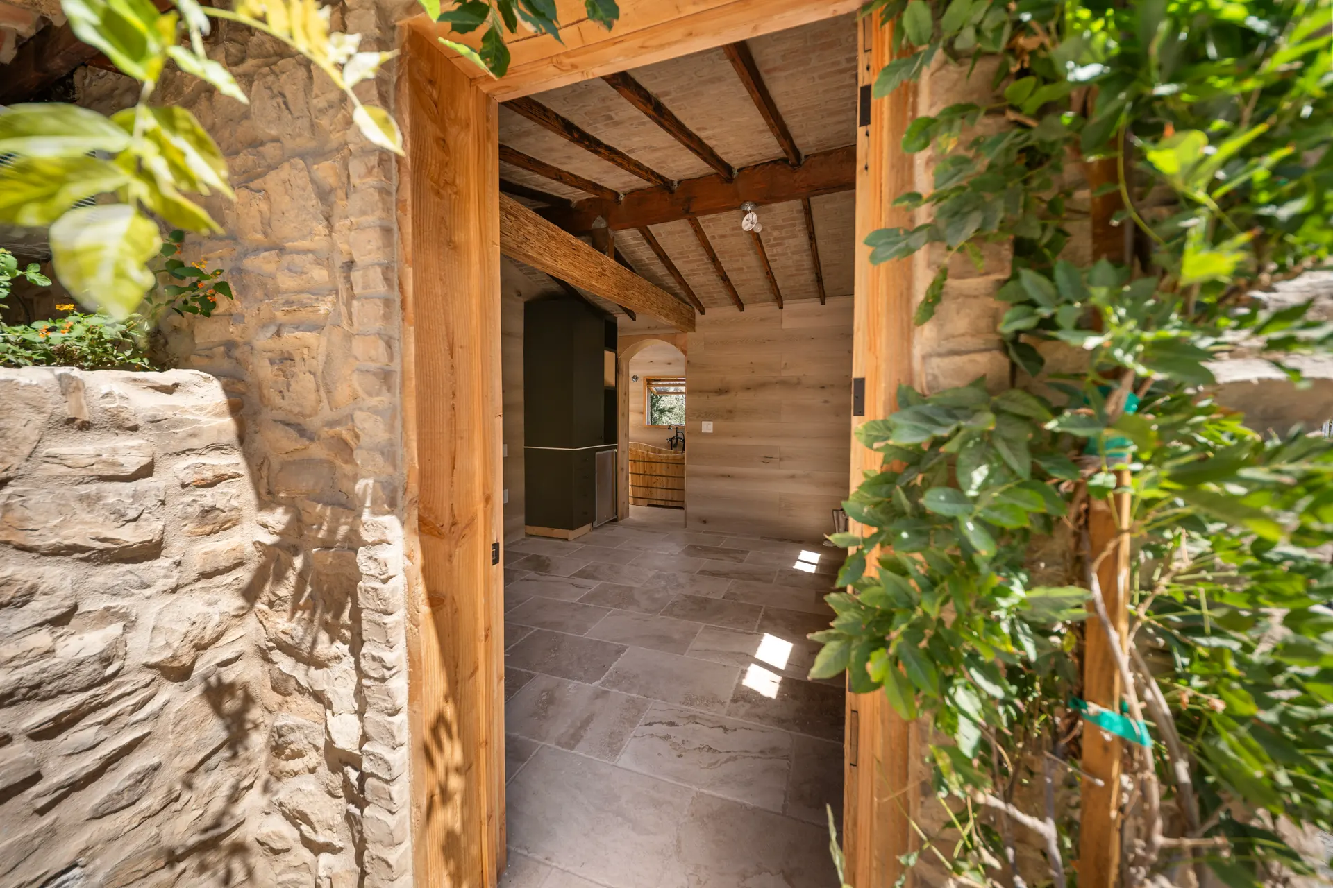 Stone passage looking through a timber doorway into a tiled room beyond
