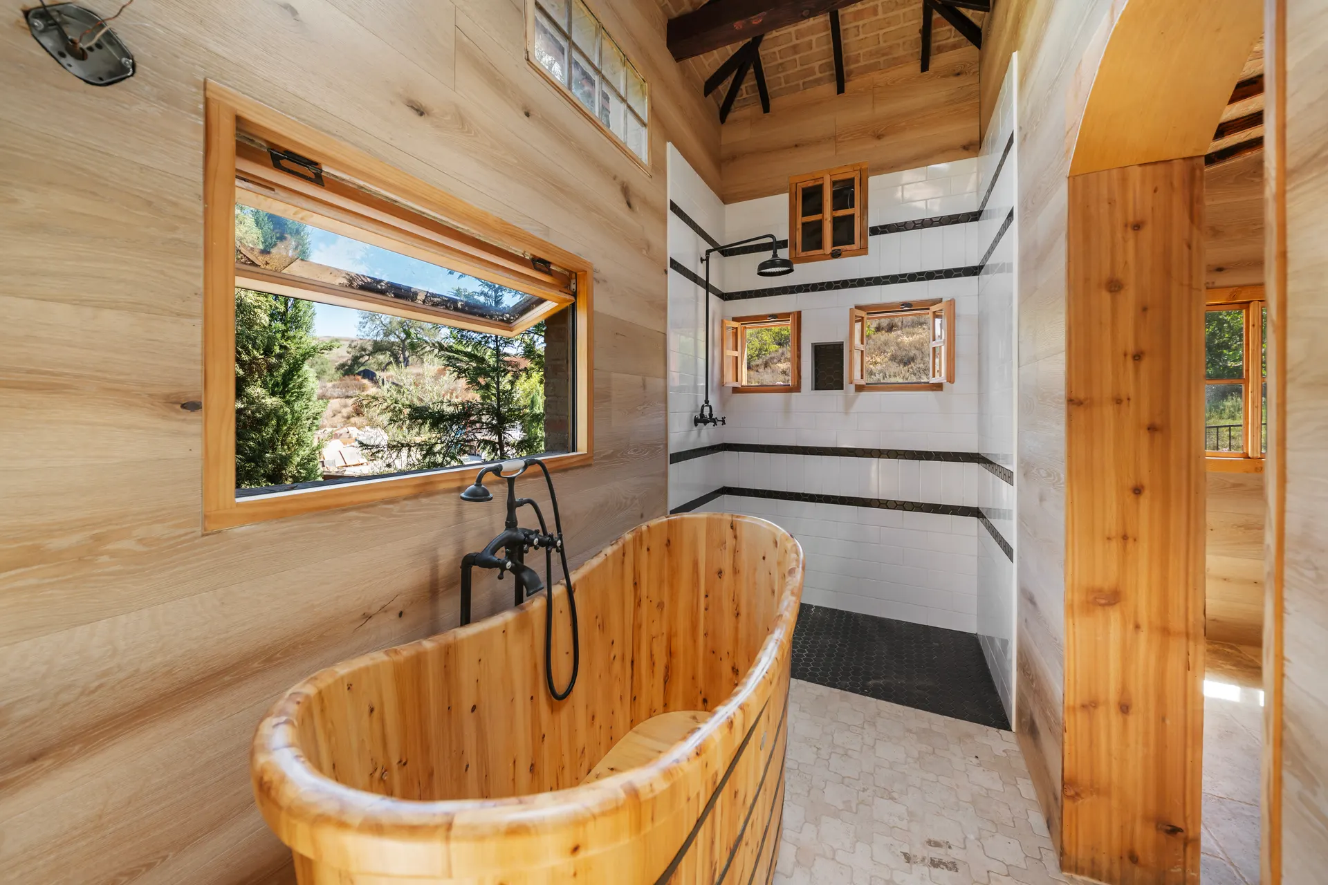 Wooden soaking tub with the tiled shower passage visible beyond