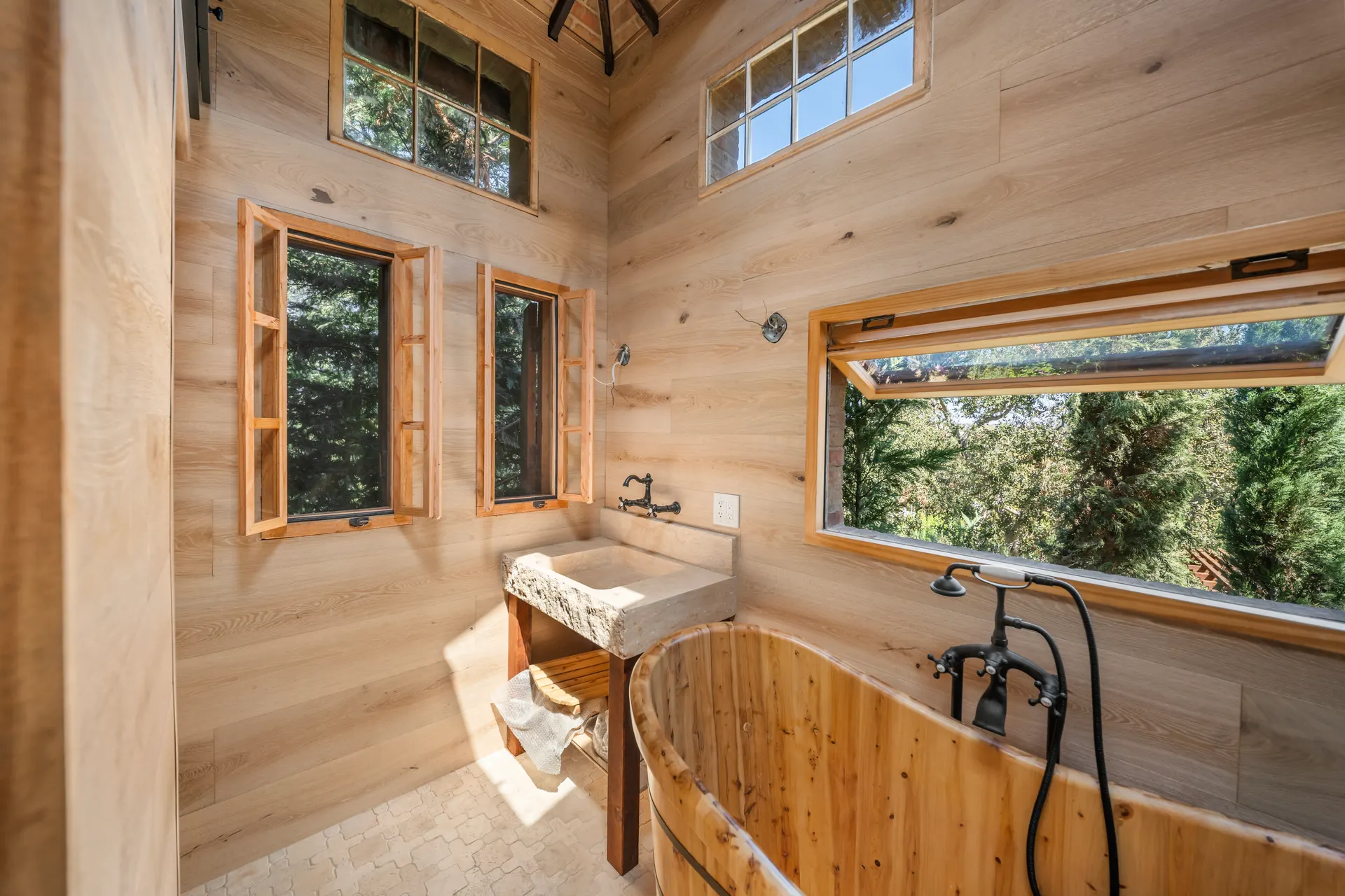 Stone basin and wooden soaking tub below a long window