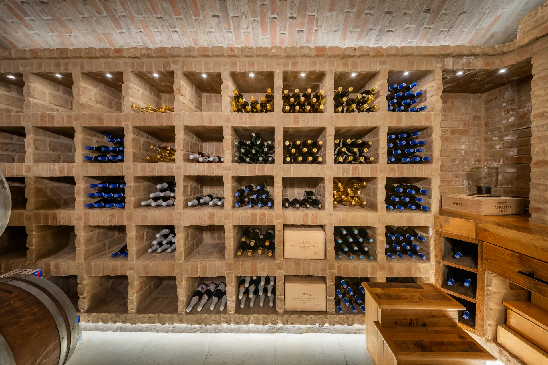 Wall of timber cubby racks filled with bottles, lit from within